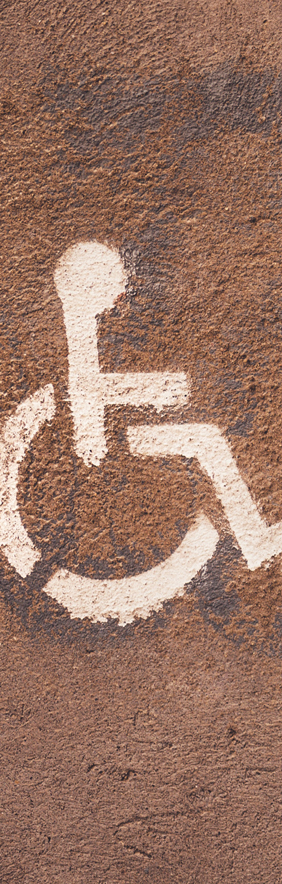A white stencil of a person in a wheelchair against a concrete background