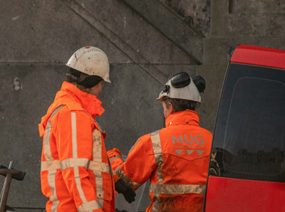 Two people in high-visibility clothing working together are pictured from behind