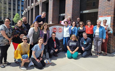 A group of people poses for a photo in front of PSAC Headquarters, 233 Gilmour in Ottawa.