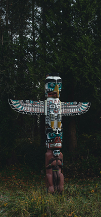 A colourful West-Coast totem pole featuring the image of a bird and and outstretched wings