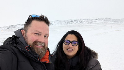 Aaron and Anu smile at the camera against a snowy backdrop 