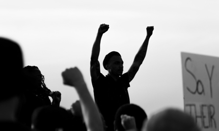 La silhouette d’un homme levant les poings au milieu d’une foule qui manifeste