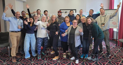 A group of smiling people with big smiles and arms outstretched pose for a photo