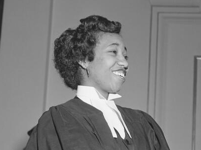 Violet King Henry, wearing judicial robes, smiles at something off-camera