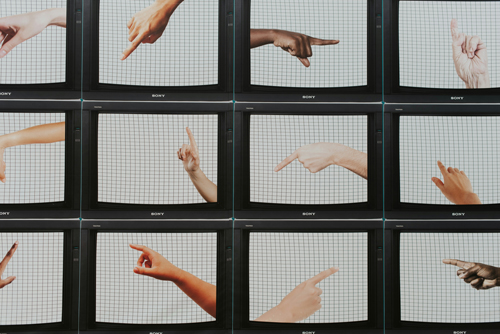 Des &eacute;crans de t&eacute;l&eacute;vision, sur lesquels on voit des mains de diff&eacute;rentes couleurs en train de signer, sont dispos&eacute;s &agrave; la mani&egrave;re d&rsquo;une grille. 