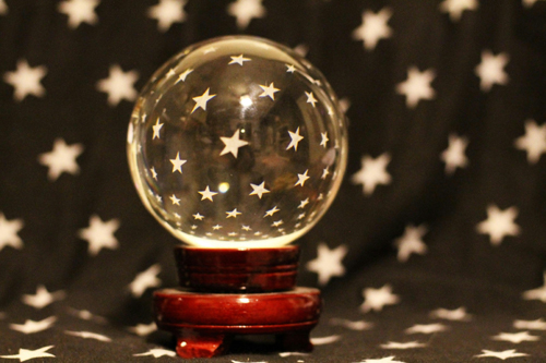 A crystal ball sits on a table surrounded by stars